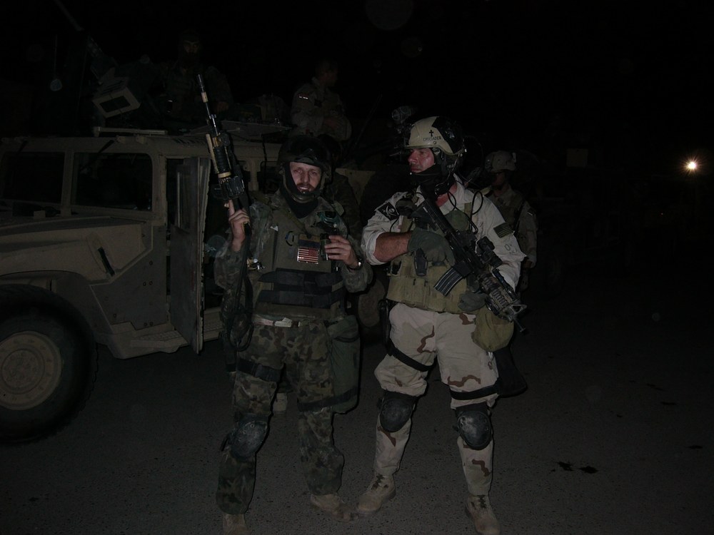 Nocna operacja przy Humvee - żołnierz w polskim mundurze obok Amerykanina w pustynnym kamuflażu