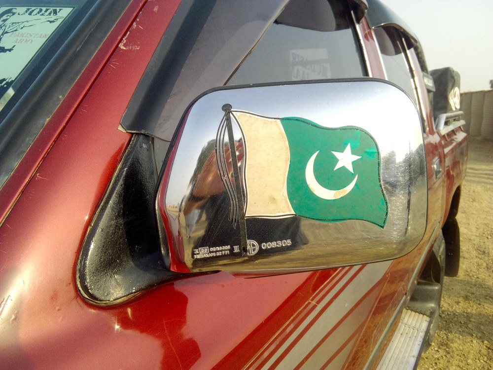 Naklejka z flagą Pakistanu na lusterku terenowego auta, w odbiciu fotografujący